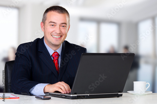 Young happy businessman working in his office
