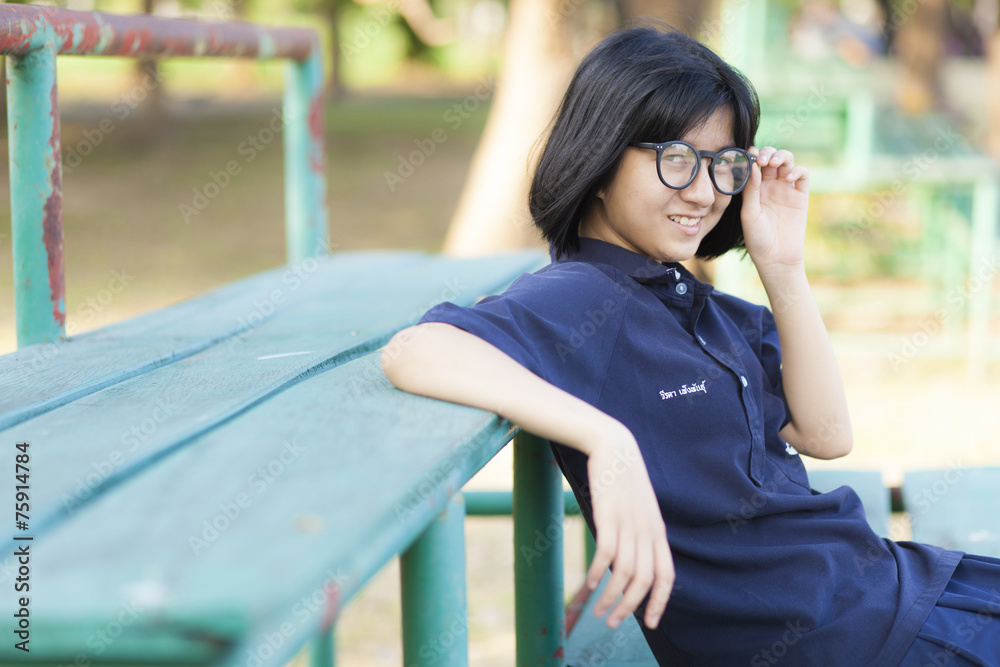 Girl wearing glasses sitting on the bench.