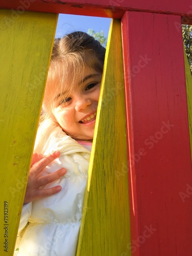 Bambina che sorride dietro staccionata colorata