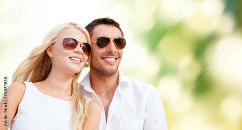 happy couple in shades over green background © Syda Productions