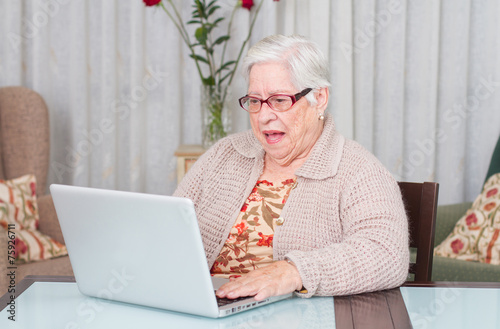 Fotografía Grandmother astonished using laptop at home.