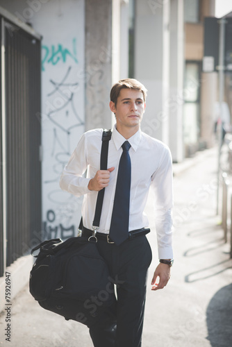 young handsome elegant blonde model man walking with sport bag