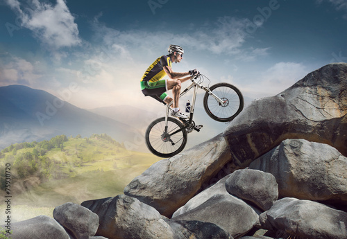Fototapeta Naklejka Na Ścianę i Meble -  Sport background. Cyclist climbing on a rock.