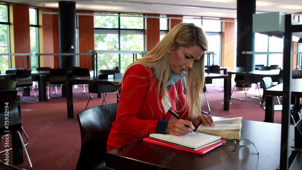 Mature student with reading glasses studying at library desk Mature student with reading glasses studying at library desk
