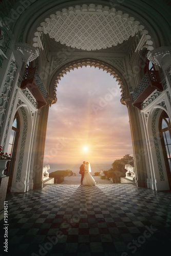 Wedding couple in the palace. Stand back in front of the sunset.