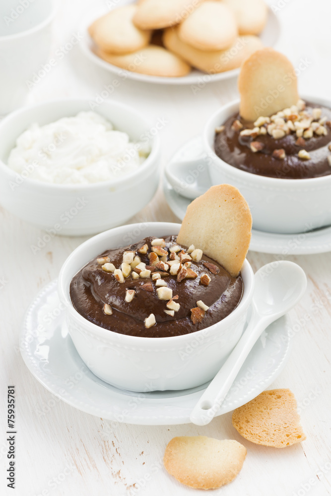 chocolate mousse with biscuits and nuts in white cups, vertical chocolate mousse with biscuits and nuts in white cups, vertical