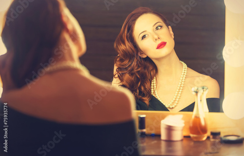 Portrait of a beautiful woman as applying makeup near a mirror © Masson