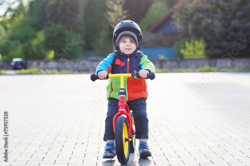 Fototapeta Naklejka Na Ścianę i Meble -  Little toddler boy learning to ride on his first bike