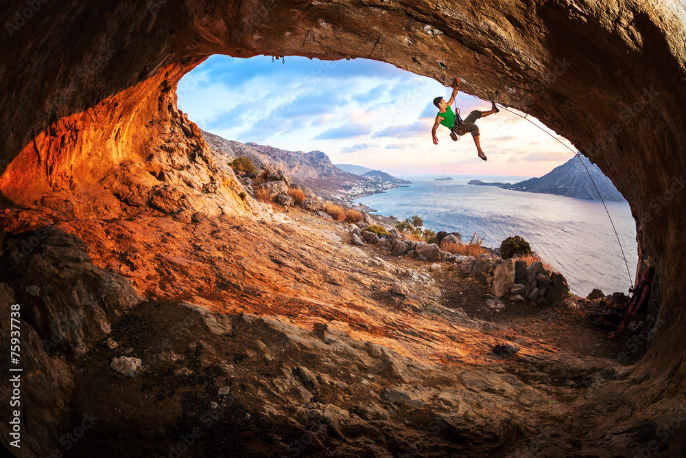 Young man lead climbing in cave before sunset - obrazy, fototapety, plakaty 