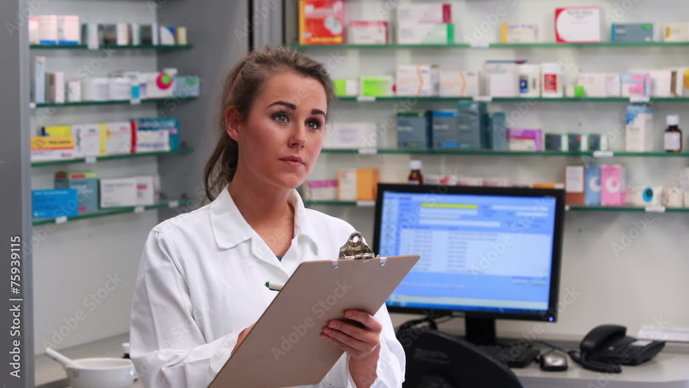Junior pharmacist writing on clipboard Junior pharmacist writing on clipboard