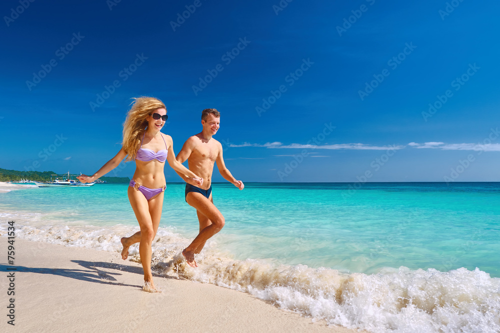 Happy Couple Running Through Waves On Beach Holiday