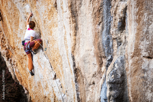 Young female rock climber struggling to take next handhold