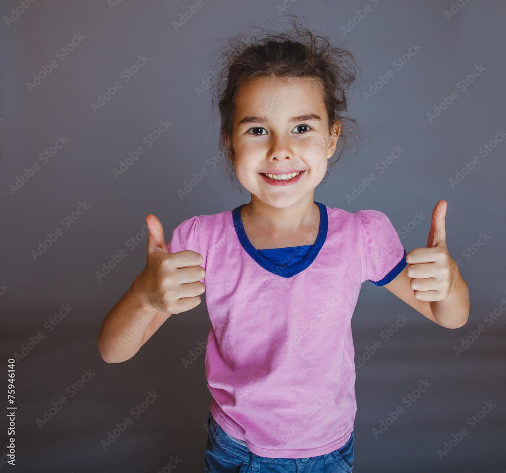 Teen girl shows gesture yes on gray background Teen girl shows gesture yes on gray background