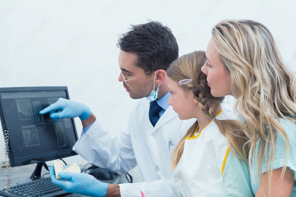 Dentist and assistant showing little girl her mouth x-ray Dentist and assistant showing little girl her mouth x-ray