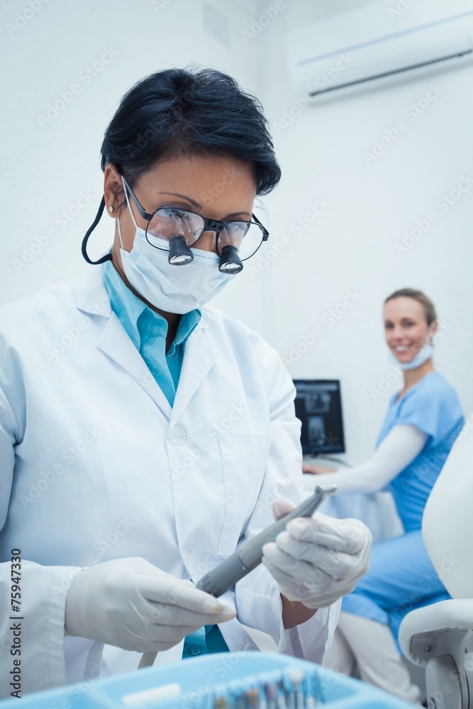 Concentrated dentist looking at dental tool Concentrated dentist looking at dental tool