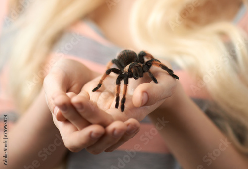 girl holding a large spider on hands