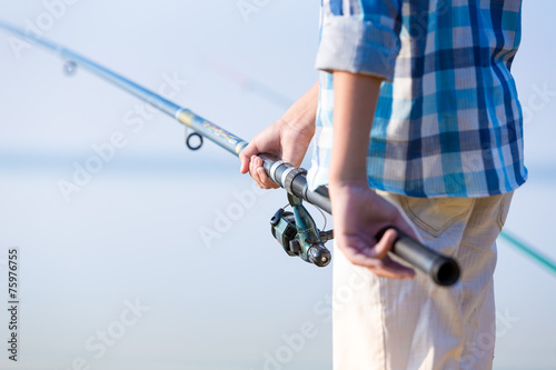 Close-up of hands of a boy with a fishing rod