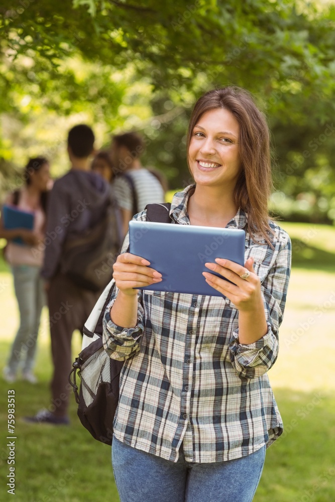 Smiling student with a shoulder bag and using tablet computer Smiling student with a shoulder bag and using tablet computer