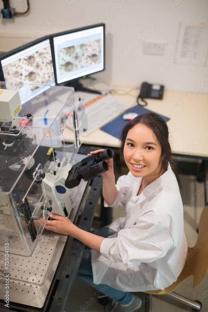 Biochemistry student using large microscope and computer