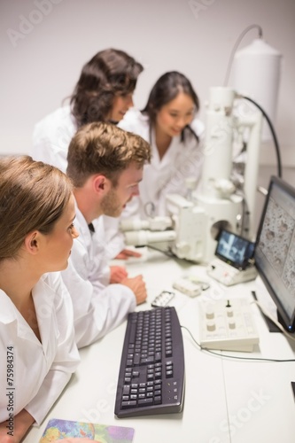 Biochemistry students using large microscope and computer