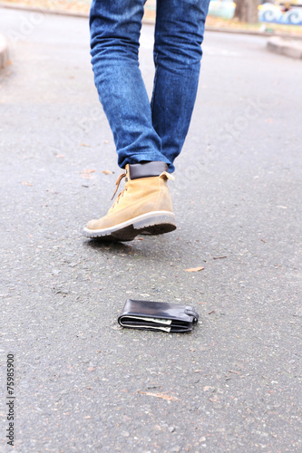 Lost leather wallet and walking male legs, outdoors © Africa Studio