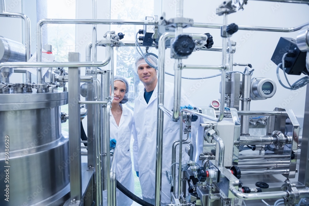 Scientist team behind metal gauge looking at camera Scientist team behind metal gauge looking at camera