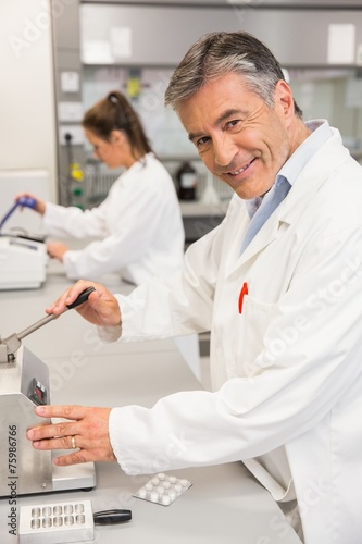 Pharmacist using press to make pills