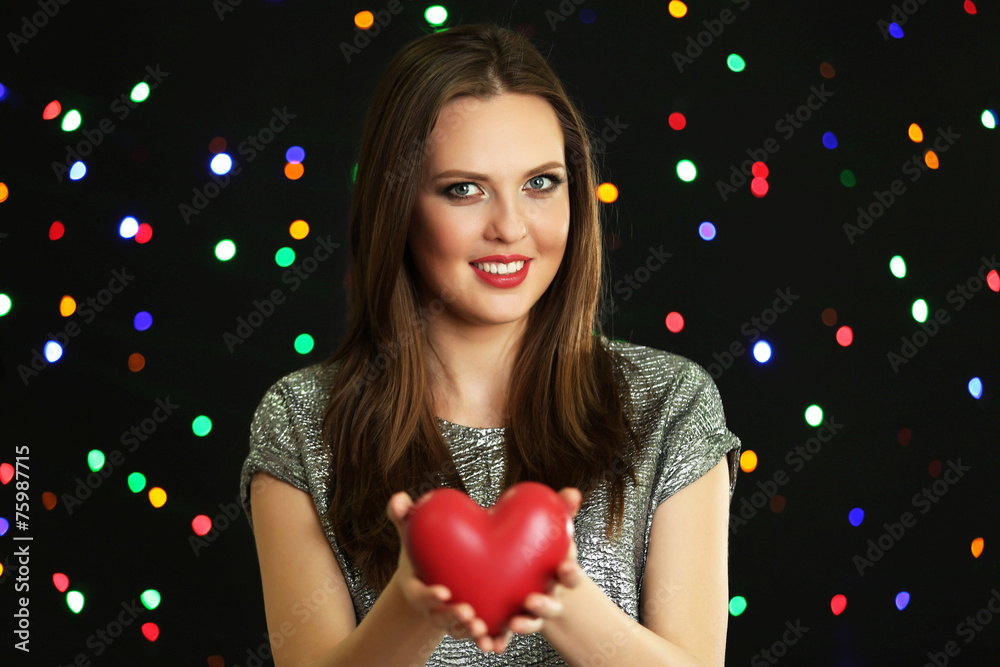 Smiling girl holding decorative heart on lights background Smiling girl holding decorative heart on lights background