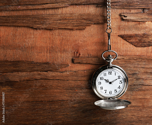Silver pocket clock on wooden background