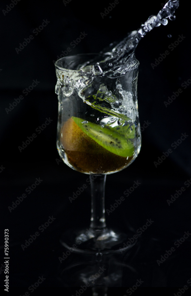 Fresh Kiwi fruit splash pure water in wine glass. Abstract water shape form when it splash. Very useful infused water contain Vitamin C Fresh Kiwi fruit splash pure water in wine glass. Abstract water shape form when it splash. Very useful infused water contain Vitamin C