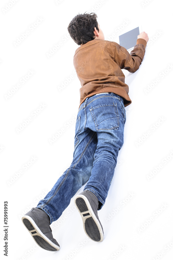 Fototapeta premium Handsome boy using tablet while lying down on the floor.