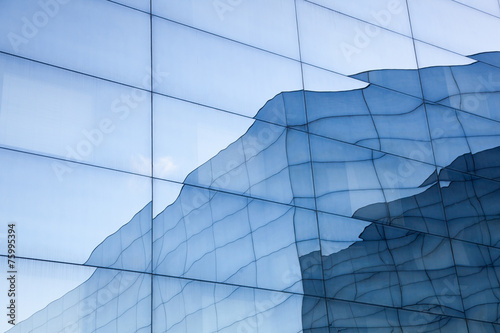 facade of modern glass building with reflections of blue sky and