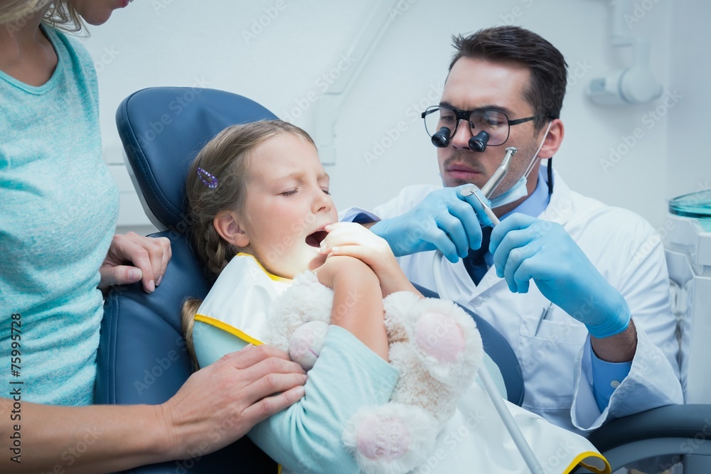 Dentist examining girls teeth with assistant Dentist examining girls teeth with assistant