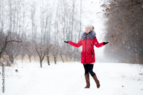 Happy smiling female in red winter jacket enjoys the snow, outdo