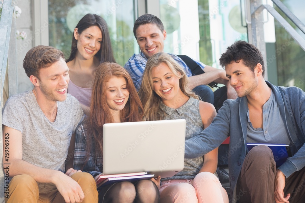 Happy students looking at laptop outside Happy students looking at laptop outside