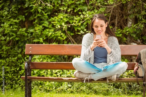 Smiling student sitting on bench text message © WavebreakMediaMicro