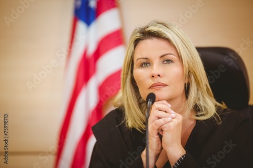 Canvastavla Portrait of a serious judge with american flag behind her