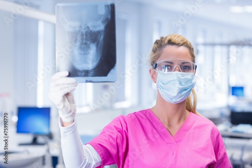 Dentist holding an x-ray and looking at camera