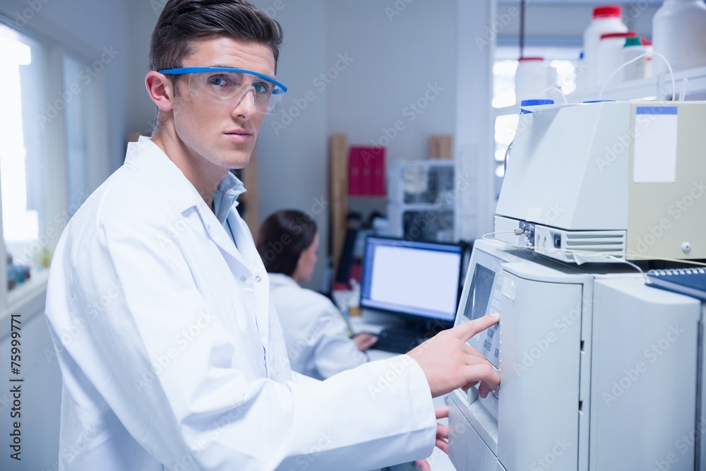 Unsmiling young chemist using the machine Unsmiling young chemist using the machine
