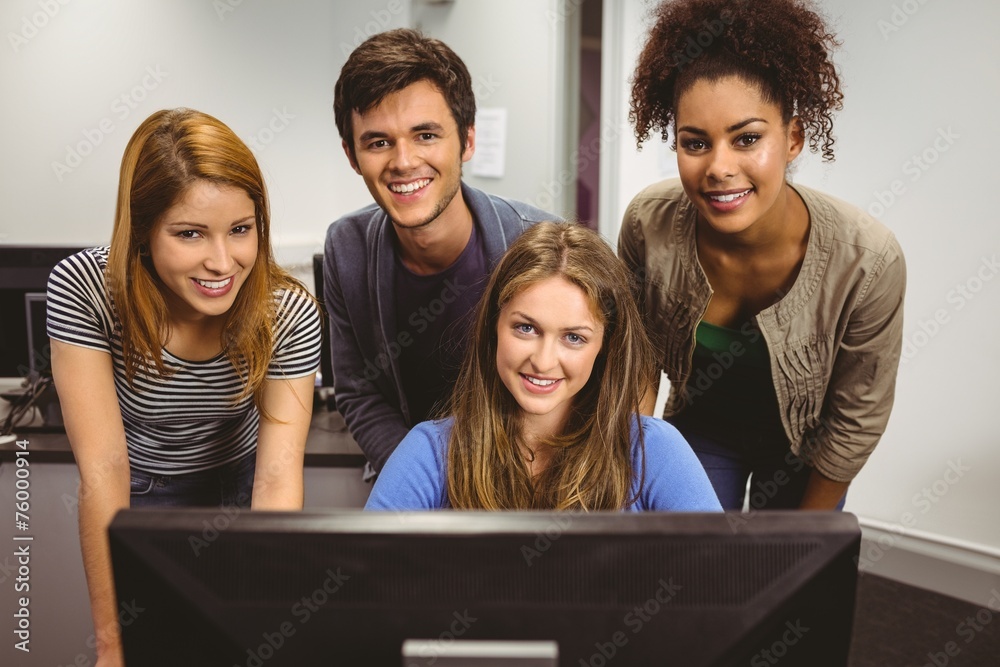 Smiling students using computer together looking at camera Smiling students using computer together looking at camera