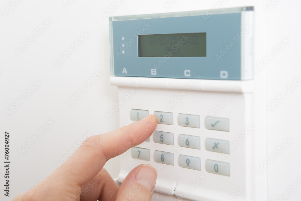 Woman Setting Control Panel On Home Security System Woman Setting Control Panel On Home Security System