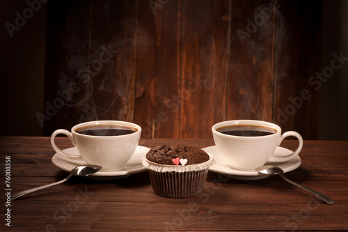 Delicious tasty cupcake and two coffe cup on wooden table
