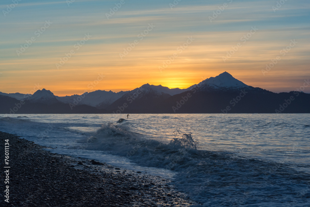 A surfer paddles out in waves on Kachemak Bay