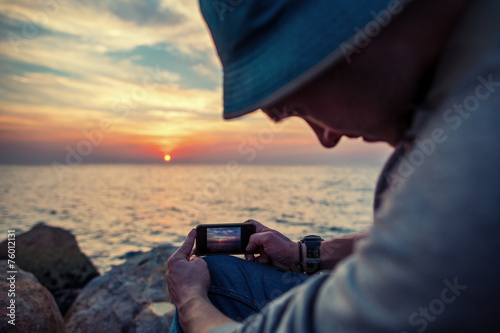 traveler making photo with mobile phone at sunset