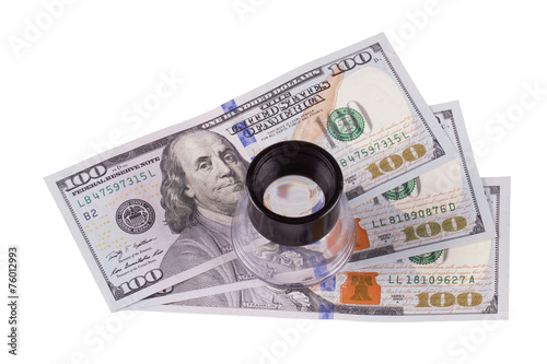 $ 100 bills and a magnifying glass to check their authenticity
