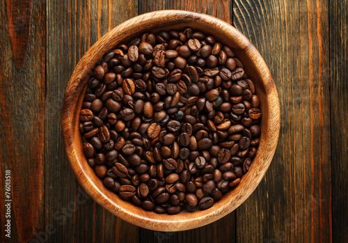 Wooden bowl with a coffee beans on wood close up