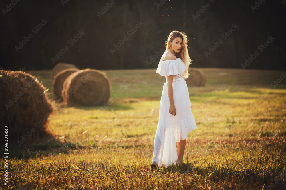 A beautiful blonde girl standing in a field on summer
