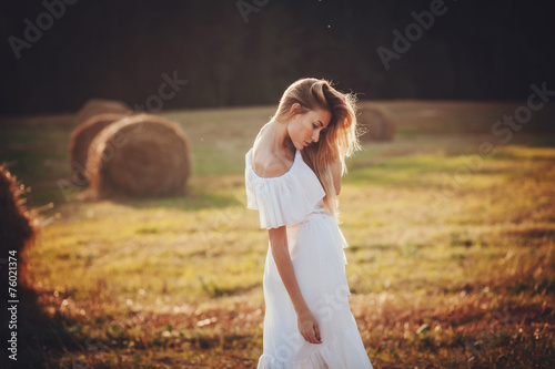 A beautiful blonde girl posing in a field on summer