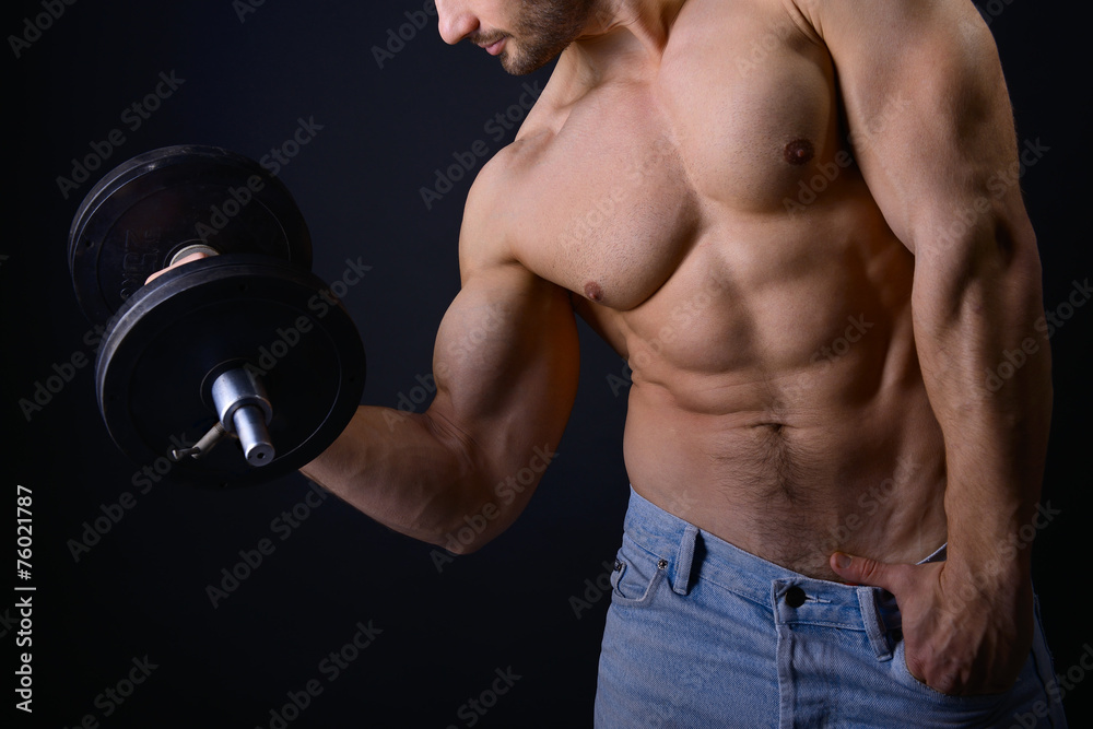 strong athletic man with perfect body posing with dumbbells on b