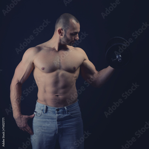 Strong athletic man with perfect body posing with dumbbells